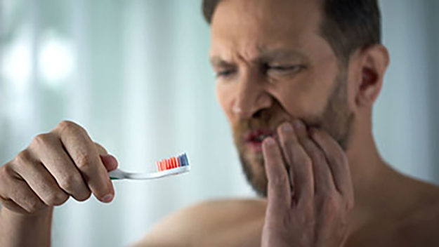 how to prevent tooth decay (1) As a man brushes his teeth, he experiences tooth pain, and wonders how to prevent tooth decay