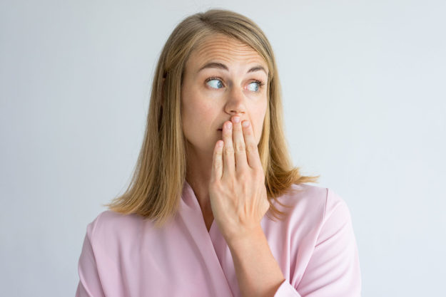 causes of bad breath woman covering her mouth to prevent causes of bad breath