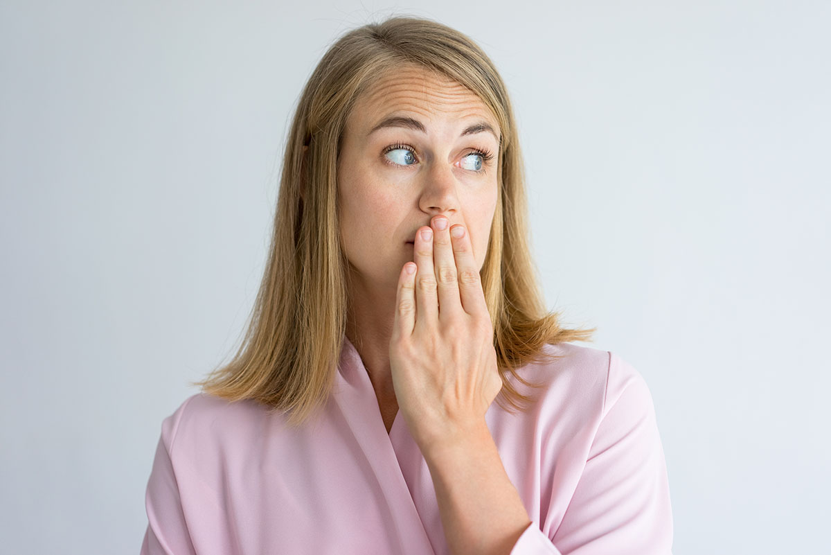 woman covering her mouth to prevent causes of bad breath