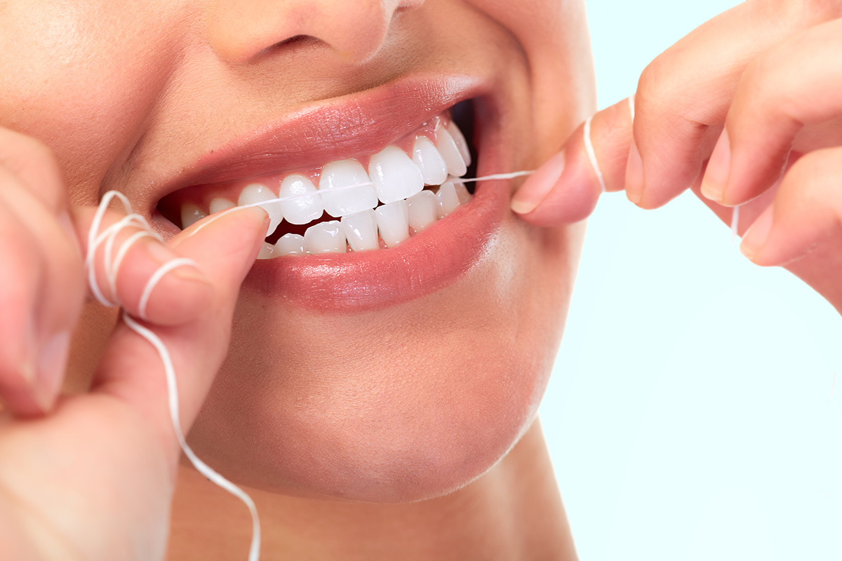 a woman begins to floss as she thinks about the benefits of flossing daily