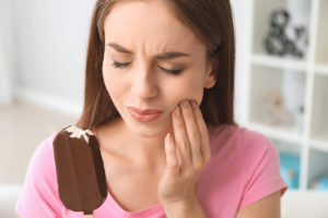 a woman holding an ice cream bar thinks about common dental problems