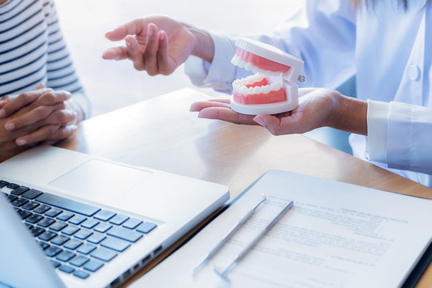 a dentist explaining to a patient the causes of receding gums