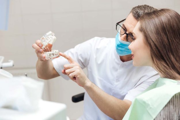 a doctor showing patient dental implants