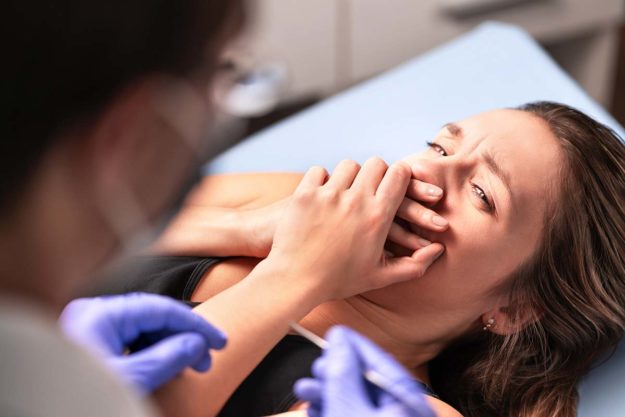 a woman scared at the dentist while struggling with dentophobia
