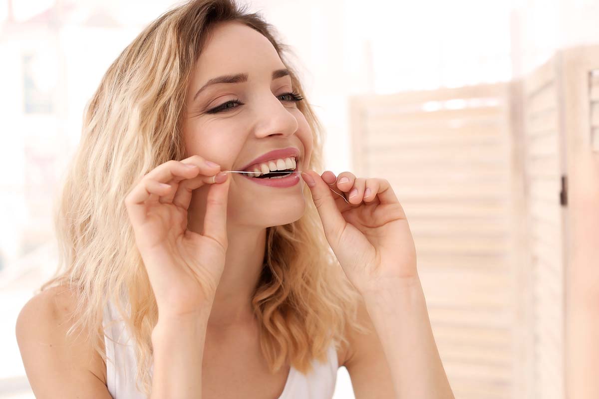 a woman flossing as a ways to reduce plaque
