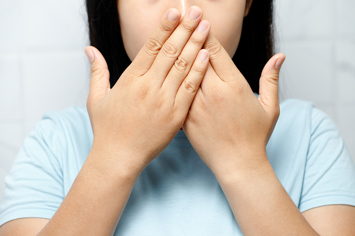 How Smoking Affects Your Teeth a woman covers her mouth after learning about the way smoking and teeth interact